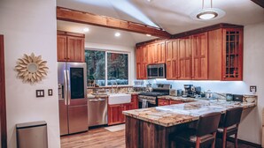 A modern kitchen with wooden cabinets, stainless steel appliances, and a large island with bar stools.