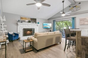 Un salon avec une cheminée, un canapé, une table basse et un coin repas avec des chaises.