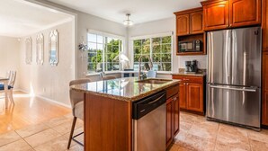 A modern kitchen with a large island, stainless steel appliances, and wooden cabinets.