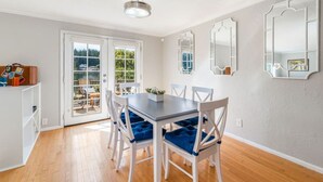 A dining area with a table and chairs, a ceiling fan, and a view through a glass door.