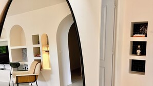 A modern interior with a dining area, a mirror reflecting the space, and a hallway leading to another room.