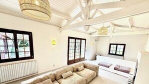A spacious room with a large sofa, a bed, and a dining area.