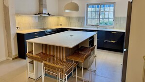 A modern kitchen with a central island, built-in appliances, and a large window providing natural light.