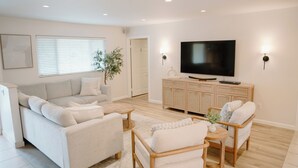 Un salon moderne comprenant un canapé, des fauteuils, une table basse, un téléviseur et un meuble.