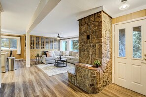 A spacious living room with a stone fireplace, a sofa, a coffee table, and a view of the outdoors.