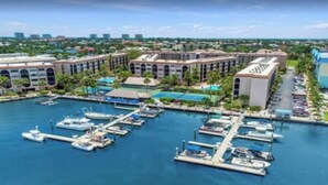 A marina with multiple docks and boats, surrounded by buildings with a modern architectural style. - Cozy 1-bedroom condo with pool access (Marco Island)