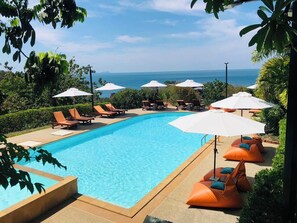 Una piscina al aire libre, sillones reclinables de piscina