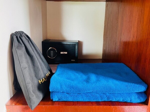 A neatly arranged room with a blue towel, a grey bag with 'HAIR' embroidered on it, and a black electronic device on a wooden surface. - Bakantiang Resort (Ko Lanta)
