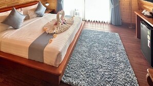 A cozy bedroom with a wooden ceiling, a bed with pillows, a decorative swan, and a television. - Bakantiang Resort (Ko Lanta)