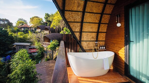 A modern bathroom with a freestanding bathtub, wooden ceiling, and a view of the surrounding area. - Bakantiang Resort (Ko Lanta)