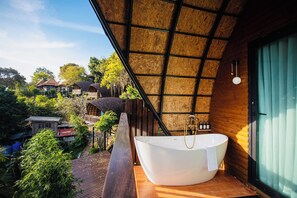 A modern bathroom with a freestanding bathtub, wooden ceiling, and a view of the surrounding area. - Bakantiang Resort (Ko Lanta)