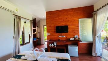 Una habitación de hotel con una cama, pared de madera, televisor, escritorio y ventana.