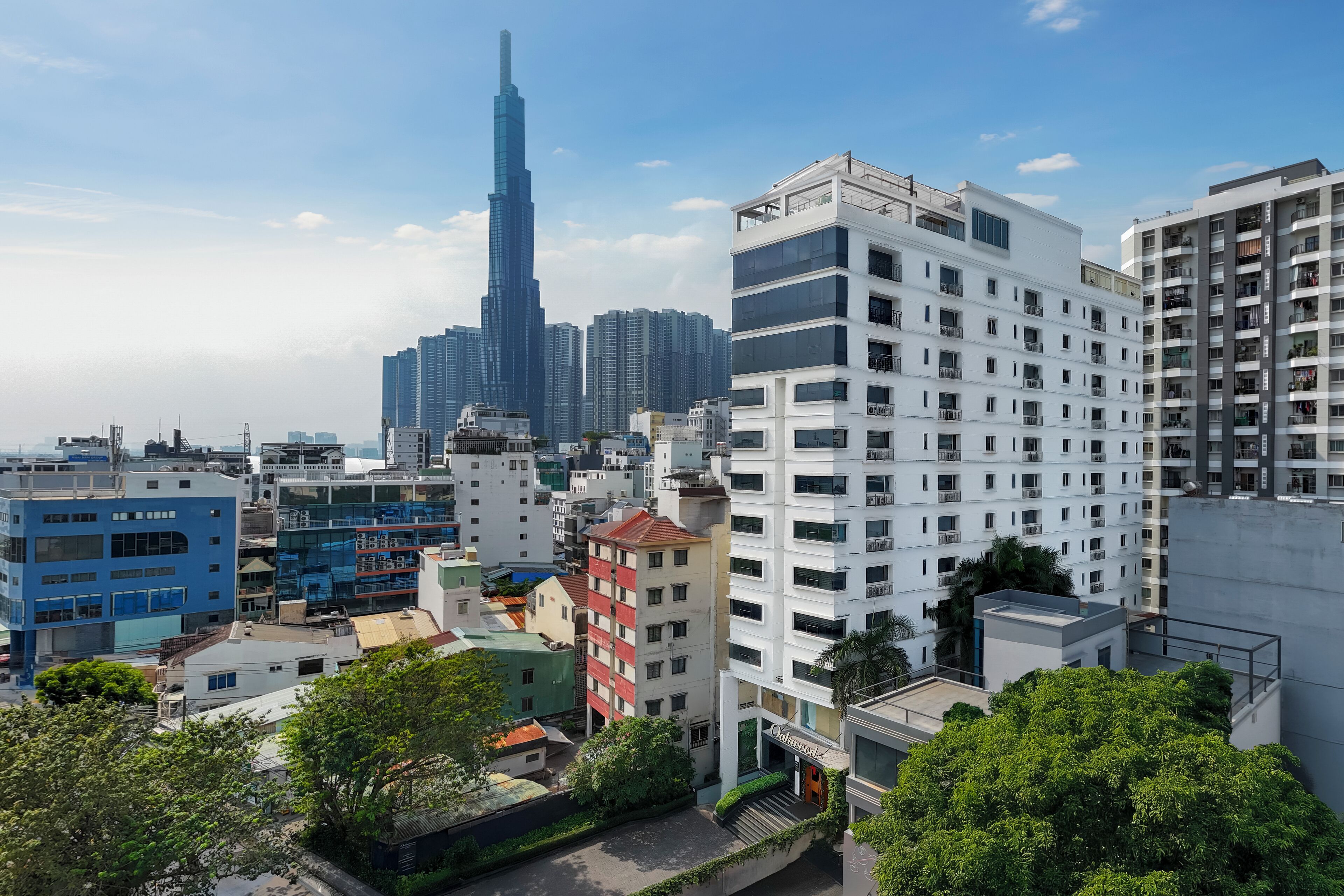 Paisagem urbana com edifícios modernos, incluindo um arranha-céu em destaque ao fundo.