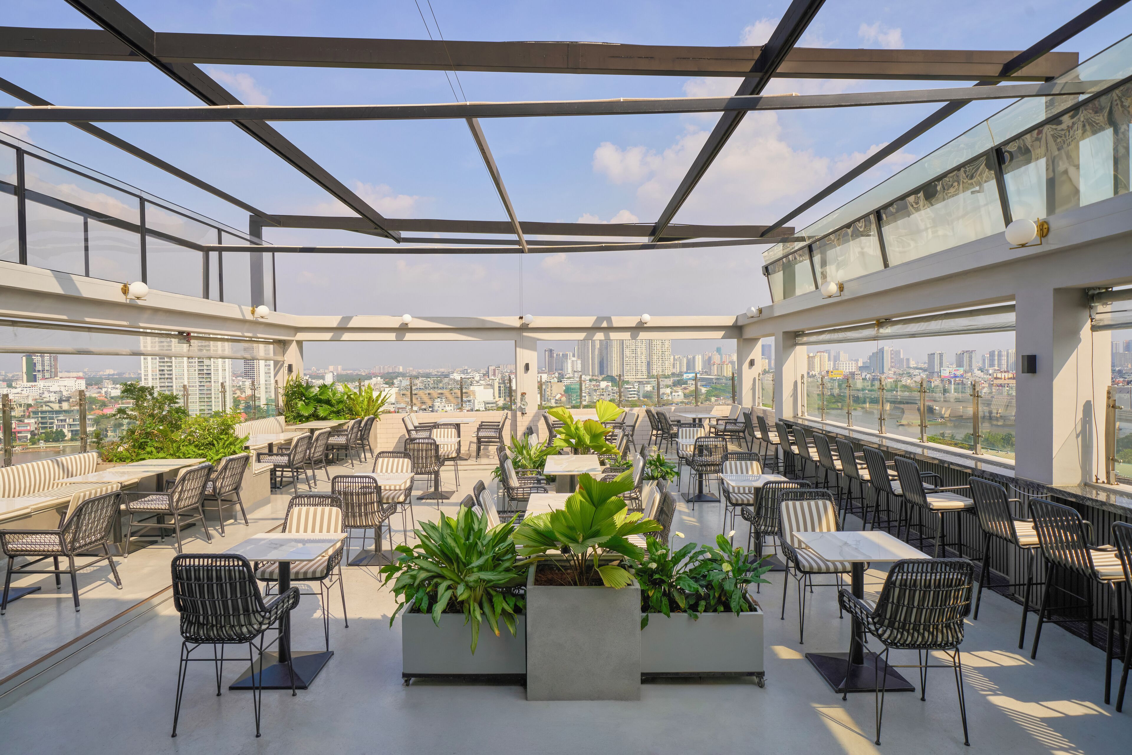 Une terrasse sur le toit, avec des espaces de détente en plein air, des plantes en pot et une vue sur la ville.