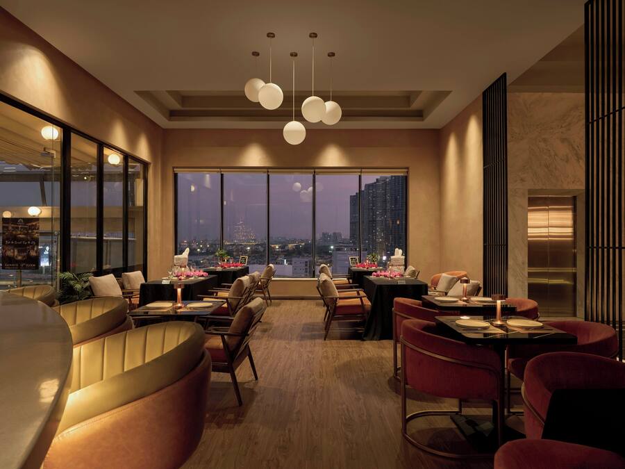 Un comedor moderno con mesas altas, sillas y vistas a la ciudad.