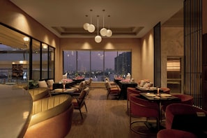 A modern dining area with high tables, chairs, and a city view.