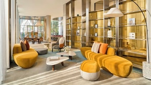 A modern hotel lobby with a seating area, a dining area, and a large bookshelf. - Oakwood Hotel & Apartments Saigon (Ho Chi Minh City)