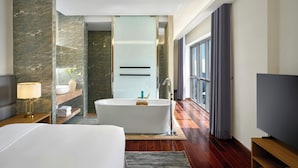 A modern hotel room with a large bed, a bathtub, a TV, and a window with curtains. - Oakwood Hotel & Apartments Saigon (Ho Chi Minh City)