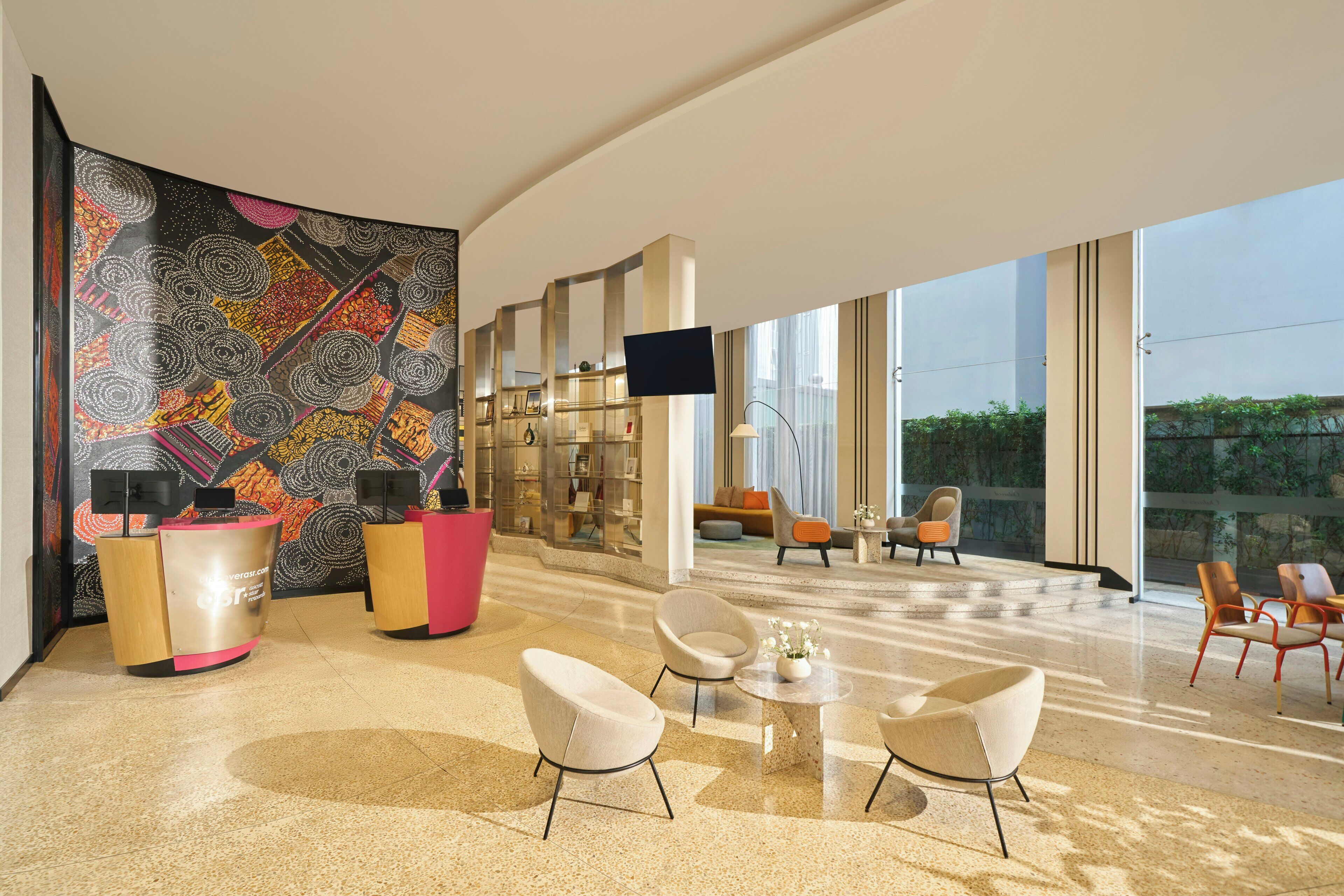 Een moderne lobby met een receptiebalie, een zithoek en grote ramen.