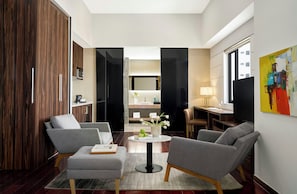 Un salon moderne avec un canapé, des fauteuils, une table basse et un téléviseur.