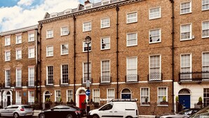 A row of terraced houses with uniform brick facades, white window frames, and small balconies.