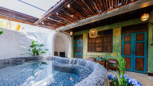 A hot tub with mosaic tiles, a wooden pergola, and a green wall with blue doors. - Teewana Resort Chiang Mai (Hang Dong)