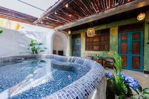 A hot tub with mosaic tiles, a wooden pergola, and a green wall with blue doors. - Teewana Resort Chiang Mai (Hang Dong)