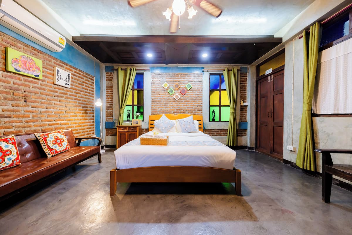 Ein Schlafzimmer mit einem hölzernen Bett, einer Bank und einer Ziegelwand.