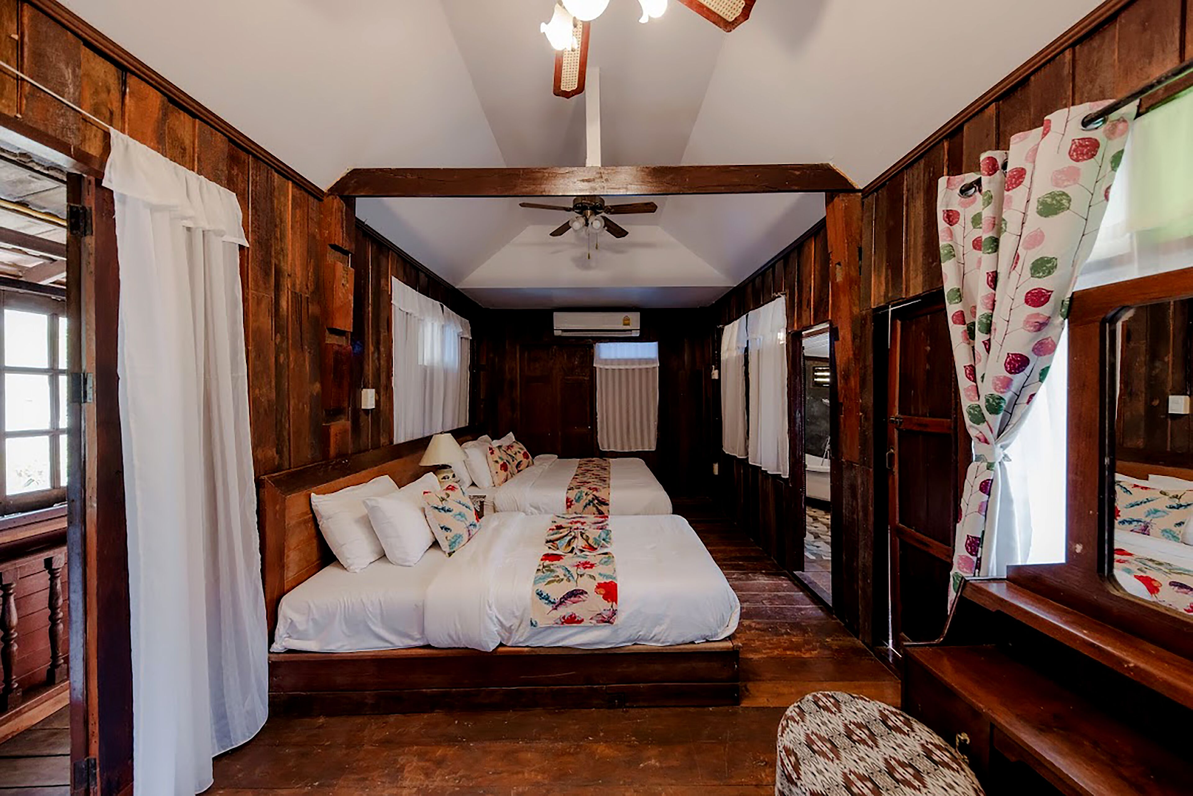 Une pièce en bois avec un lit, un ventilateur de plafond et des rideaux.