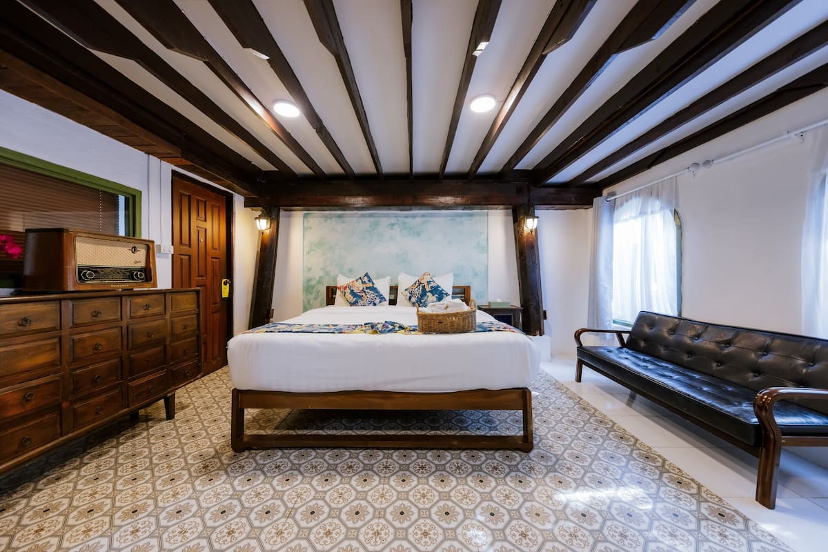 Ein Schlafzimmer mit einem großen Bett, einem Holzschrank und einer Ledersofa.