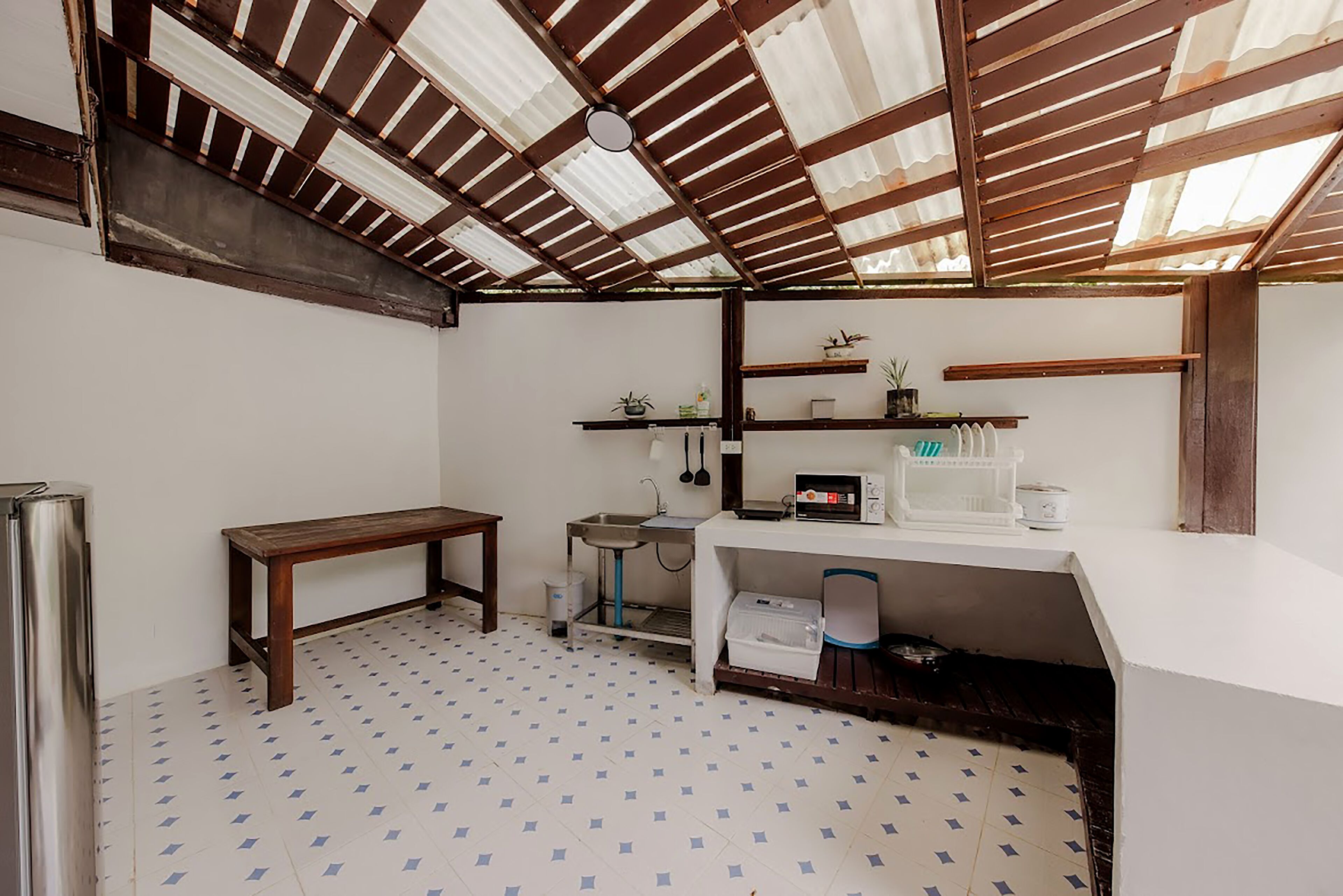Cocina compacta con un banco de madera, un lavabo y estantes con utensilios de cocina.