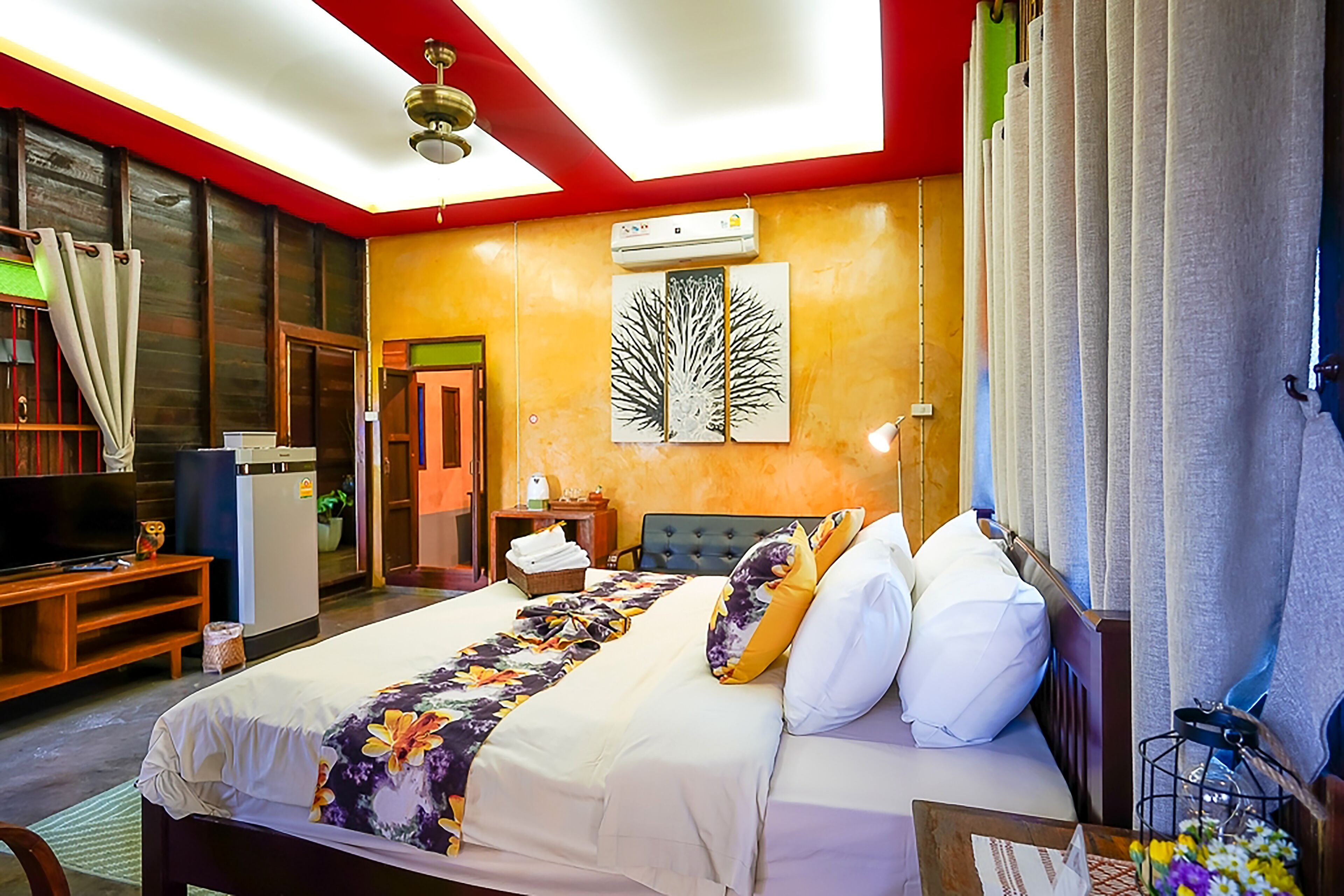 A hotel room with a bed, a desk, a television, and a window with curtains.
