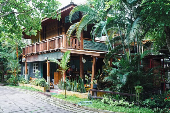 A wooden house with a balcony, surrounded by lush greenery and tropical plants. - Teewana Resort Chiang Mai (Hang Dong)