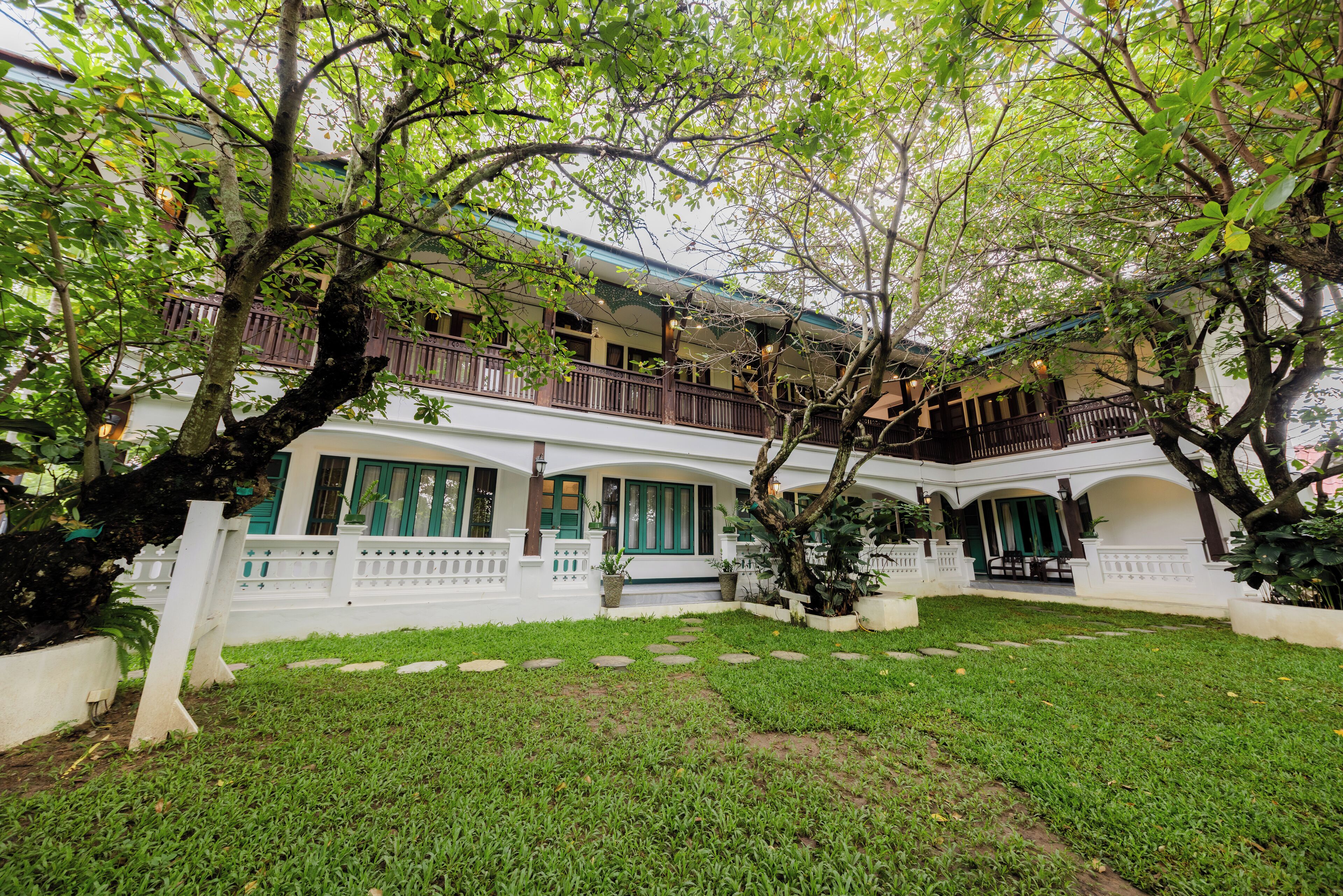 A two-story building with a white exterior, green shutters, and a balcony with a railing.