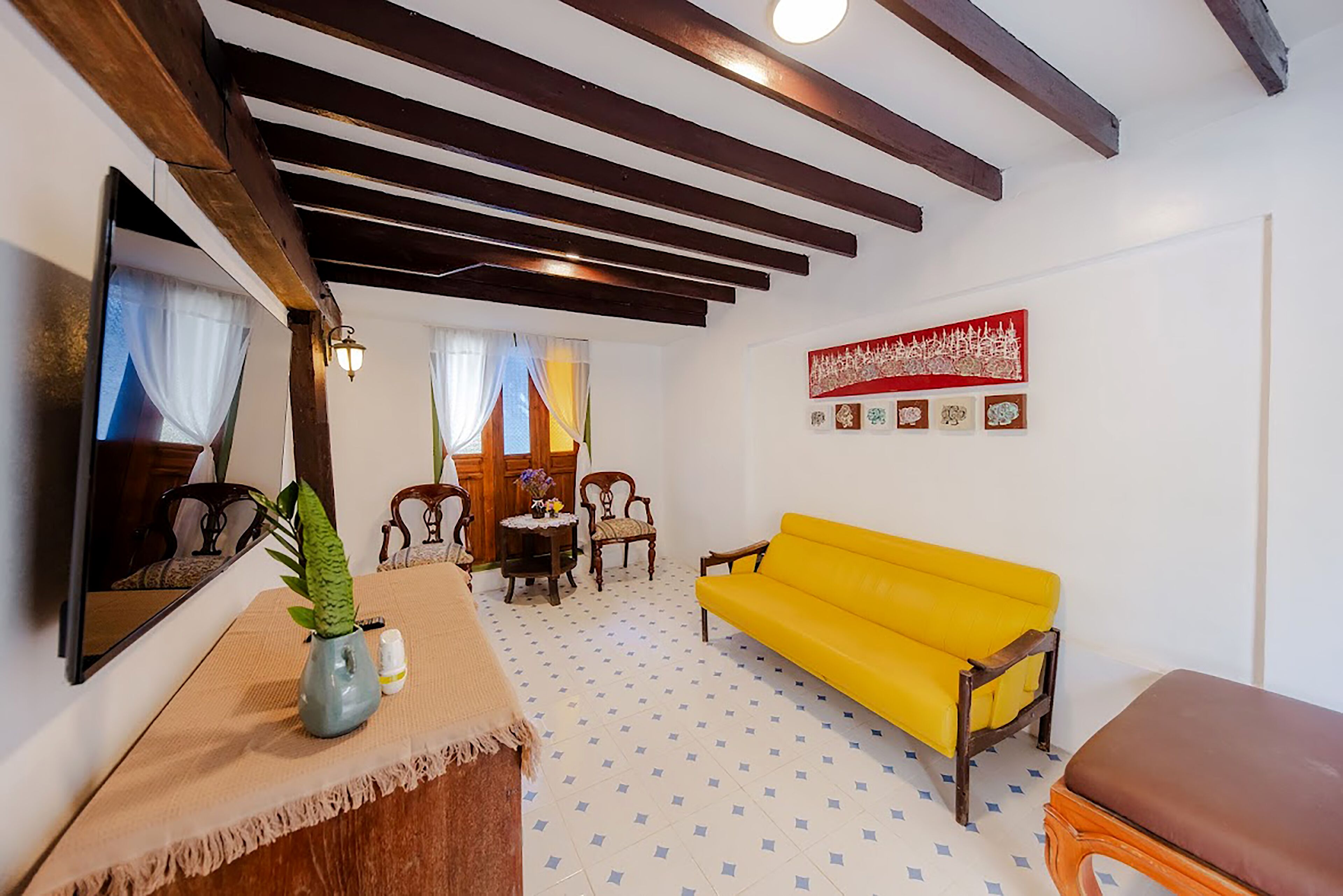 Ein Zimmer mit einem gelben Sofa, Holzmöbeln, einem Spiegel und einer Wanddekoration.