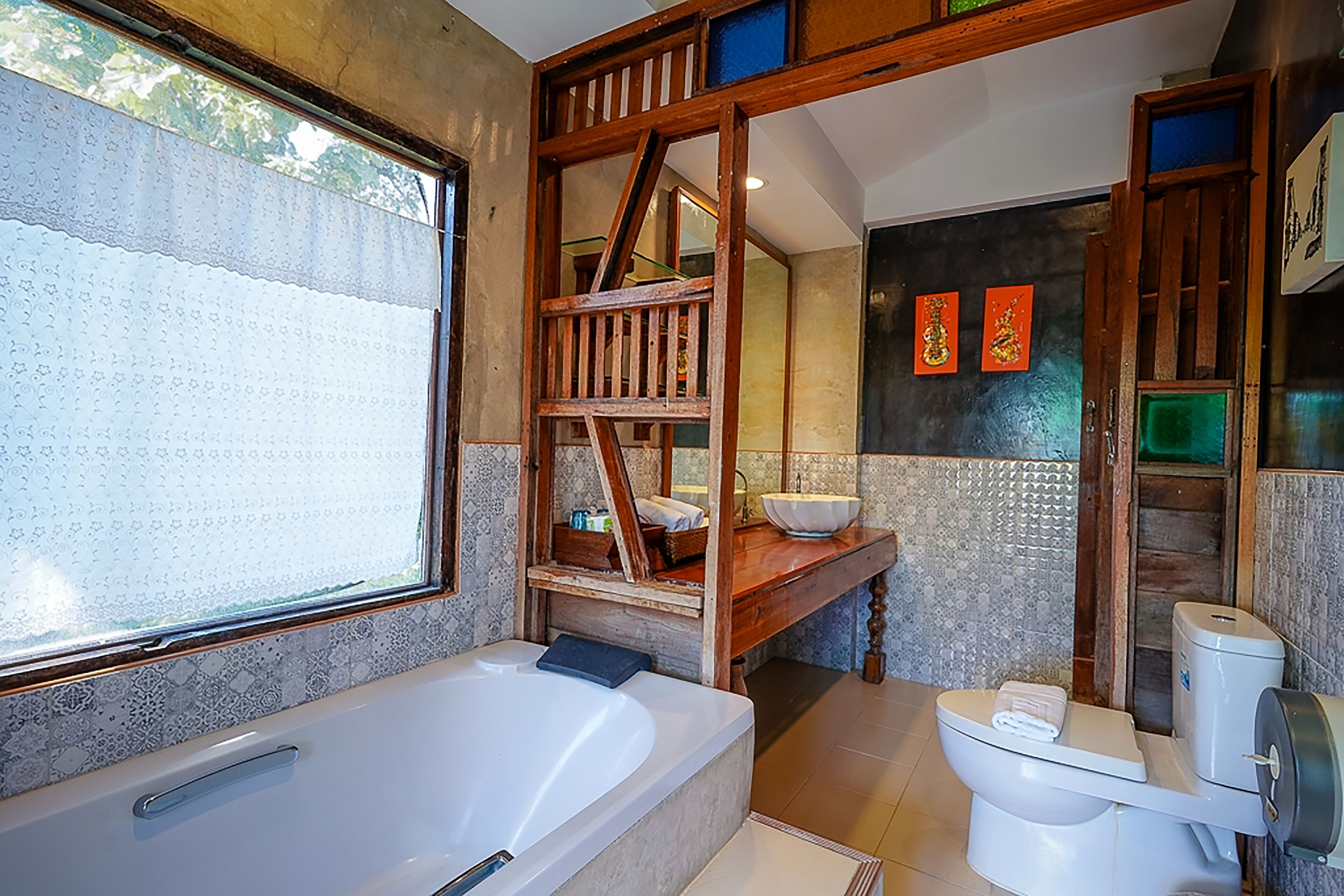 A bathroom with a bathtub, toilet, and wooden shelving unit.