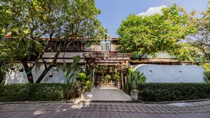 A traditional building with a wooden structure and a tiled pathway leading to a gate. - Teewana Resort Chiang Mai (Hang Dong)