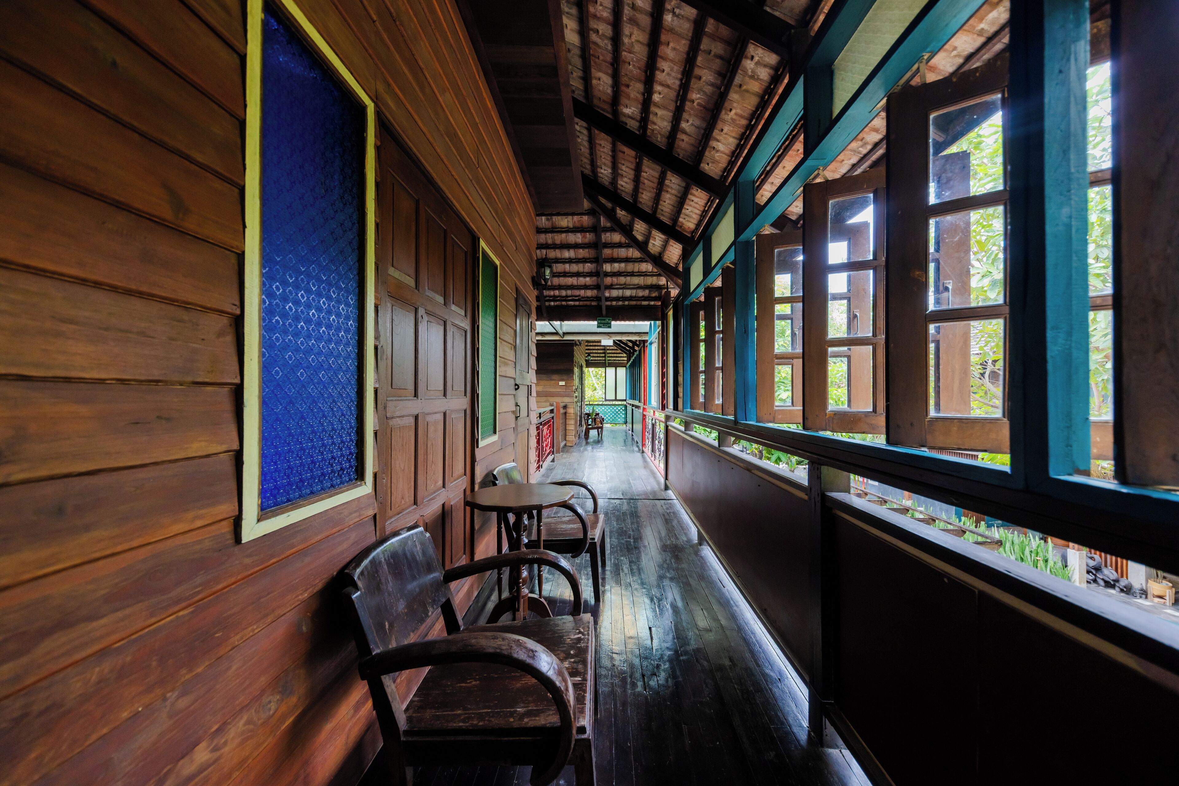 A covered corridor with wooden benches and large windows.