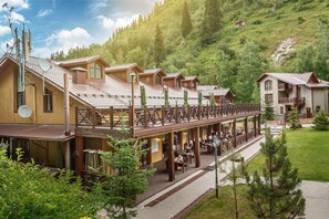A hotel with multiple wooden buildings, a covered walkway, and a mountainous backdrop.