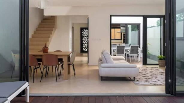 Een modern interieur met een eethoek, een bank en een trap naar een hoger niveau.