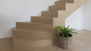 Een trap met beige treden die uitkomt op een plateau.