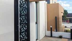 Een modern gebouw met een poort in geometrisch patroon, een betonnen pad en een minimalistisch ontwerp.