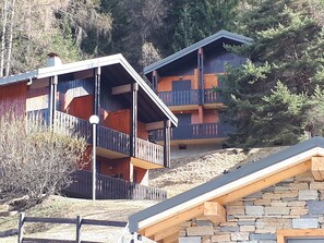 Un edificio con varios balcones, muros de piedra y una terraza de madera.