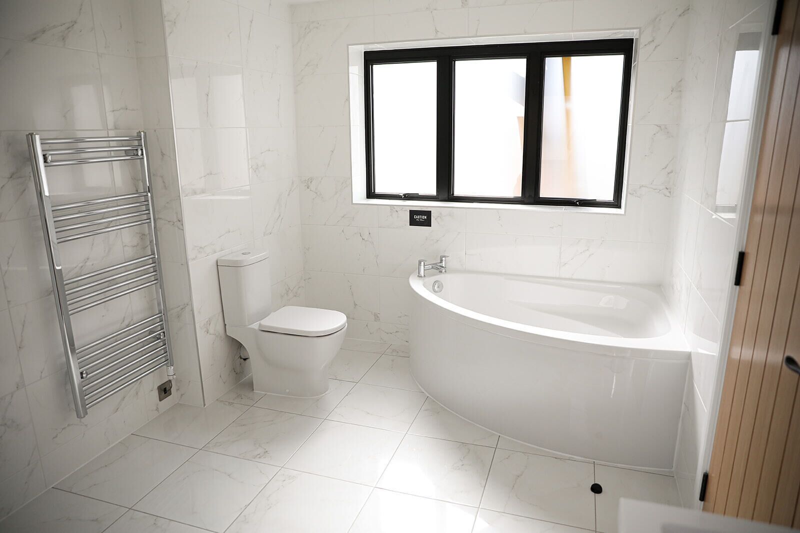 A modern bathroom with a toilet, a chrome towel rack, and a freestanding bathtub.