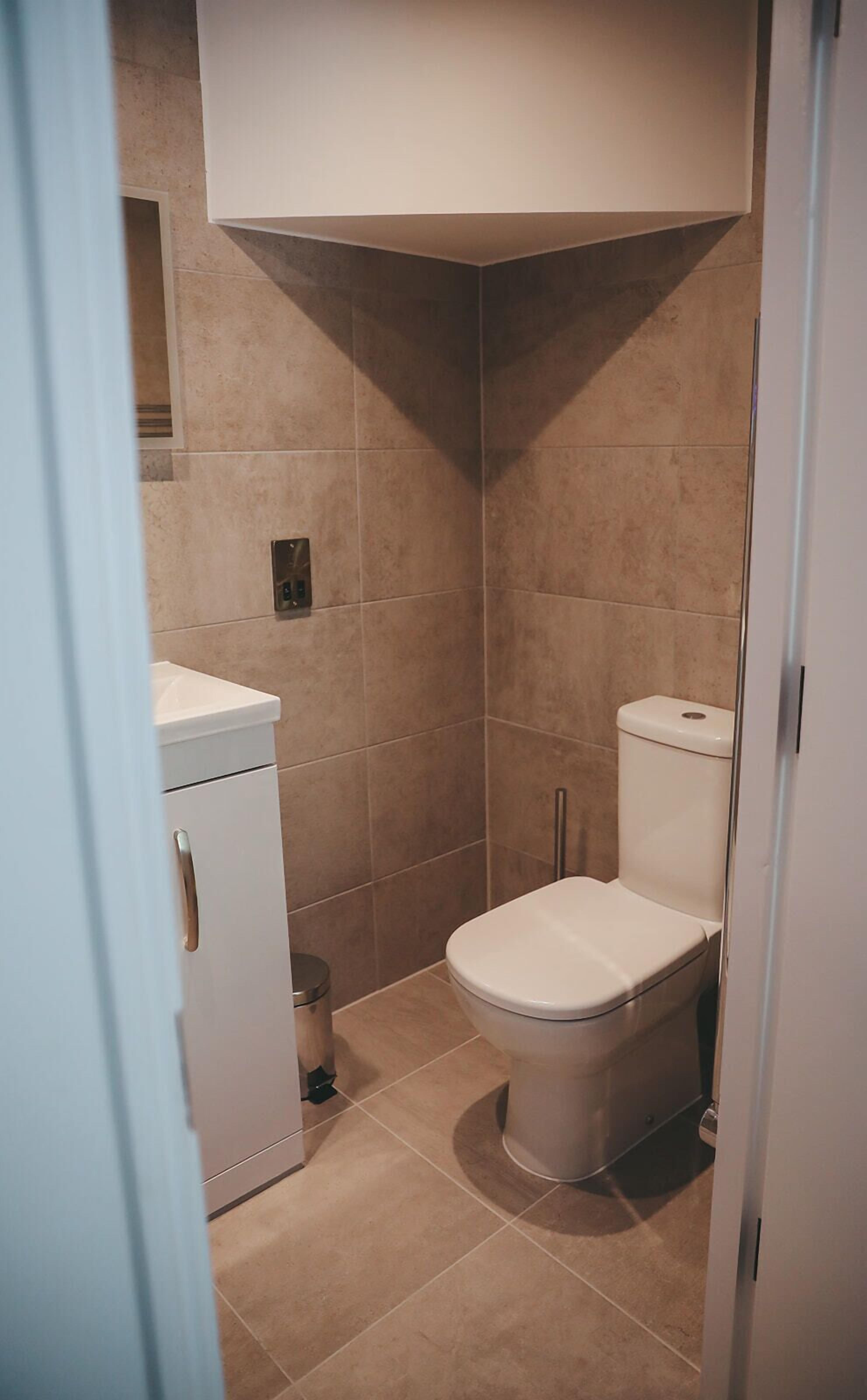 Un baño pequeño y cerrado con un inodoro, un armario pequeño y un cubo de basura.