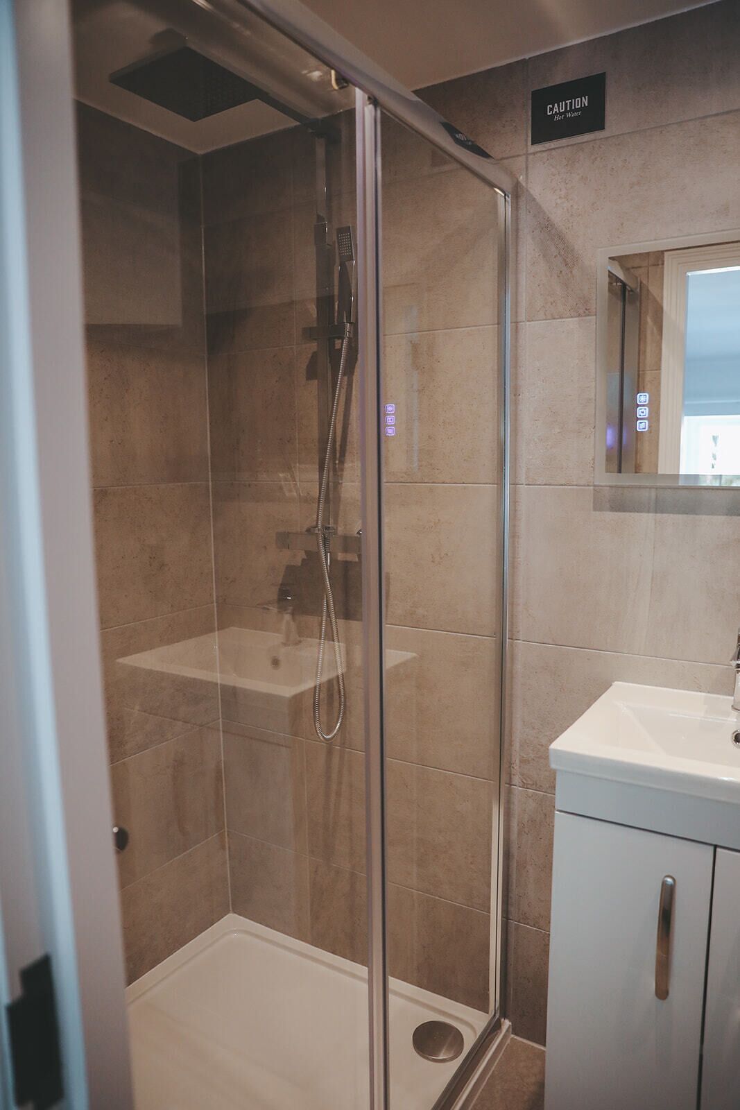 A modern bathroom with a glass-enclosed shower, a sink, and a cabinet.