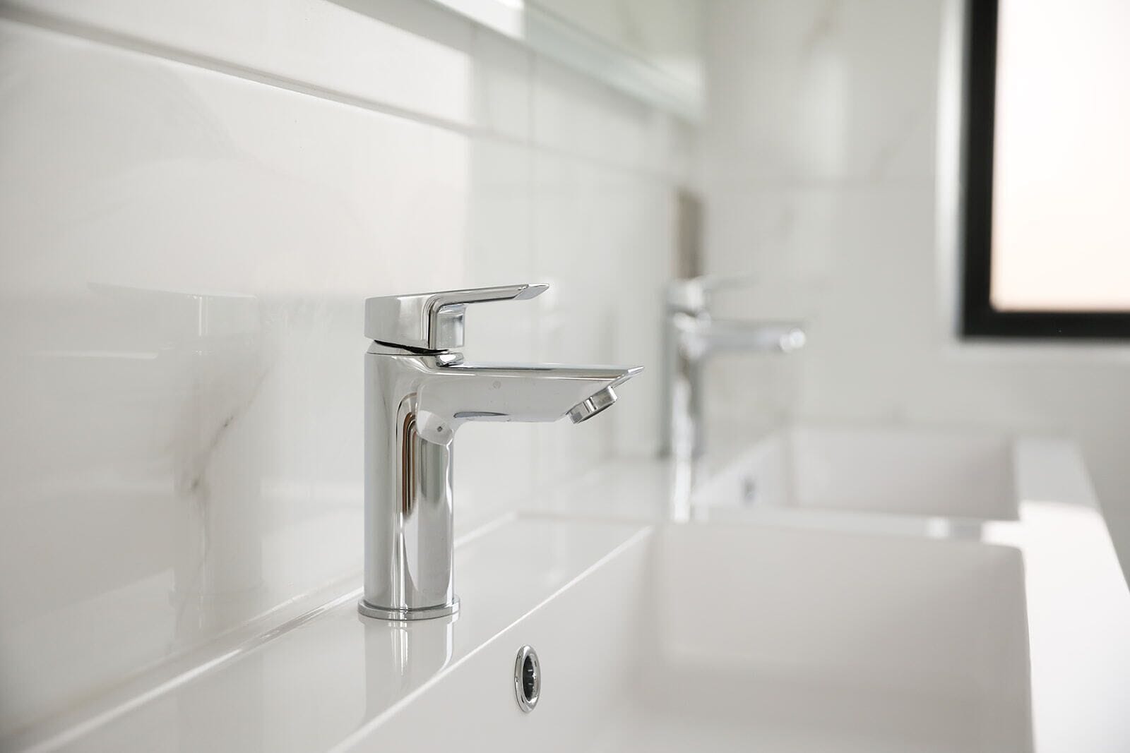 A modern bathroom with a chrome faucet and a white sink.