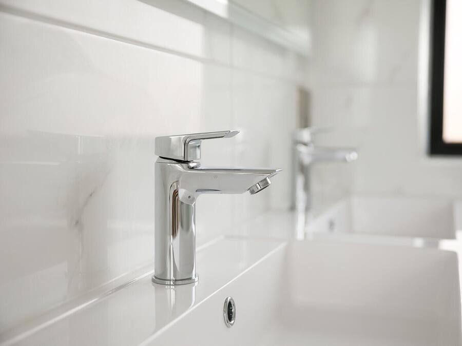 A modern bathroom with a chrome faucet and a white sink.