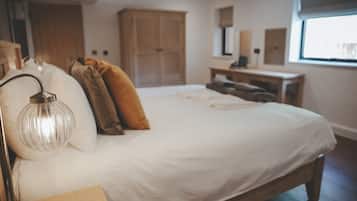 A bedroom with a large bed, a bedside lamp, a wooden nightstand, and a wardrobe.
