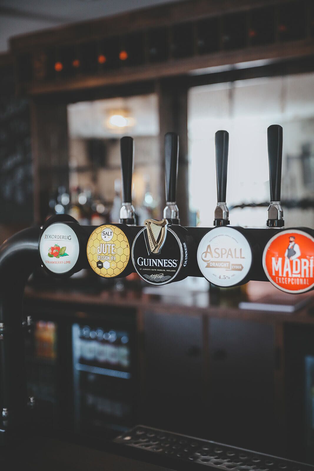 Grifo de bar con cinco tipos diferentes de cerveza, incluyendo marcas como Guinness y Asphall.